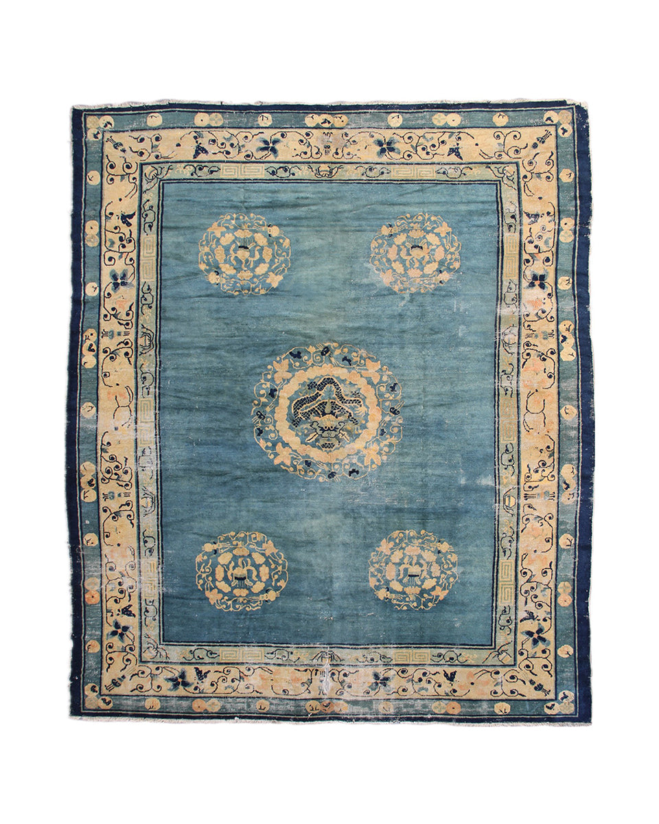 Blue and beige patterned rug with decorative border on a white background