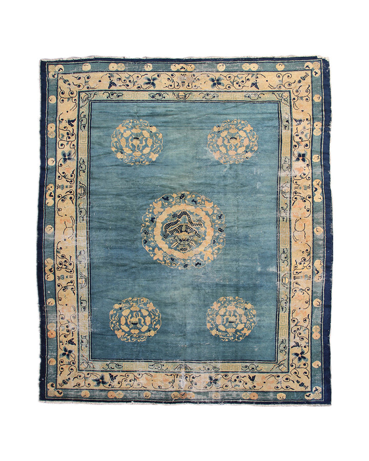 Blue and beige patterned rug with decorative border on a white background