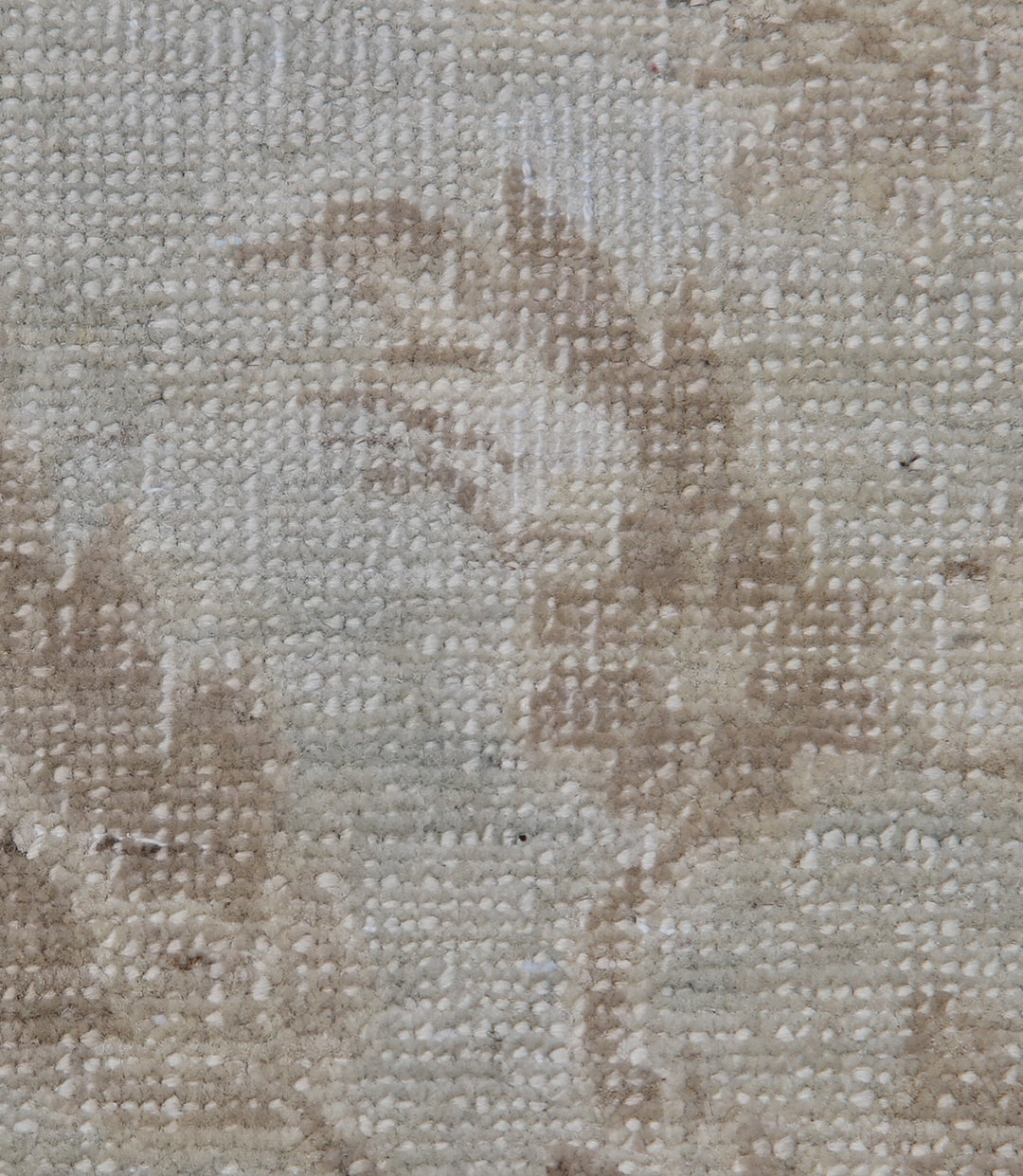 Close-up of a textured beige fabric surface with brownish stains.
