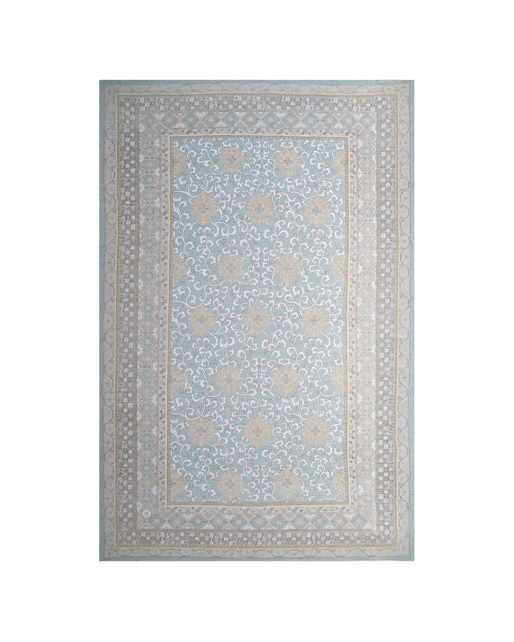 A rectangular area rug with a traditional floral pattern in light blue, beige, and gray tones, shown flat against a white background.