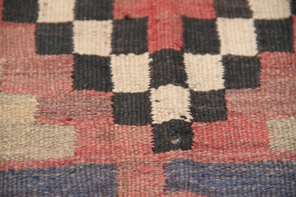 Close-up of a woven textile with a checkered pattern in red, black, and white.