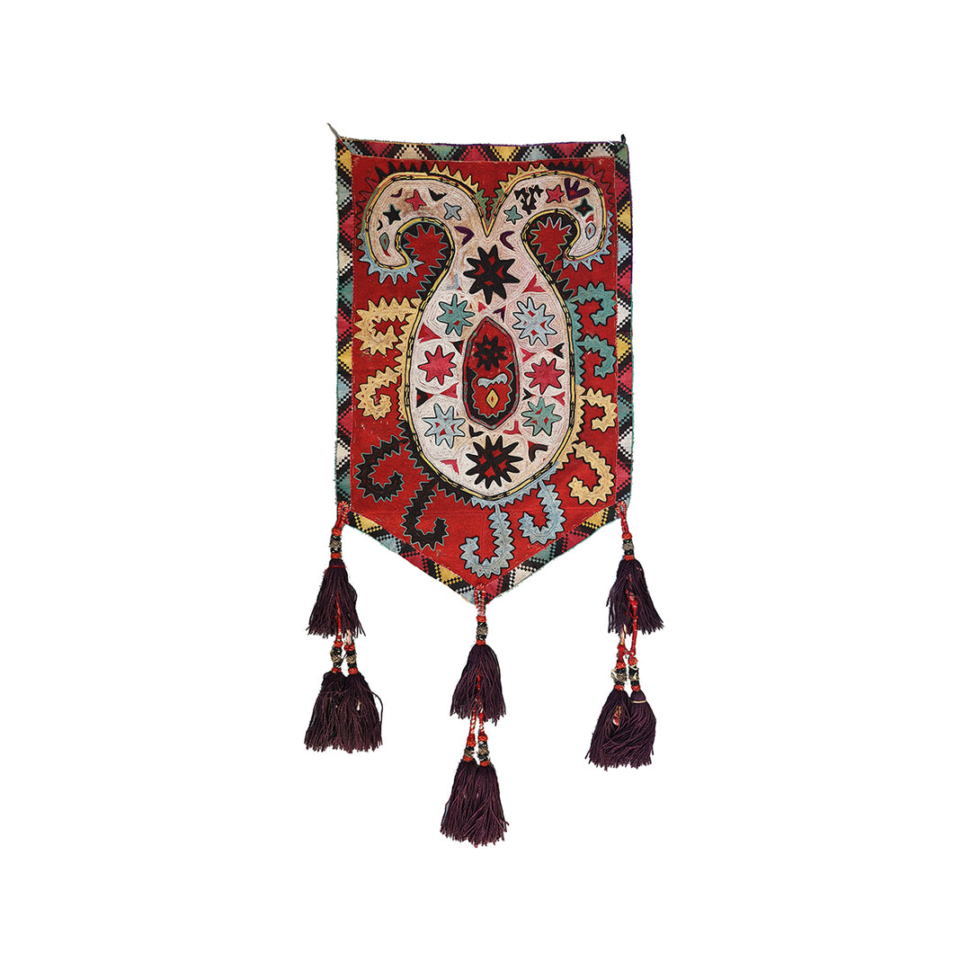 Decorative wall hanging with intricate patterns and tassels on a white background