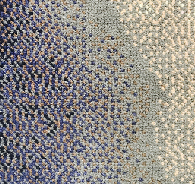 Close-up of a textured carpet with a pattern of blue, beige, and gray.