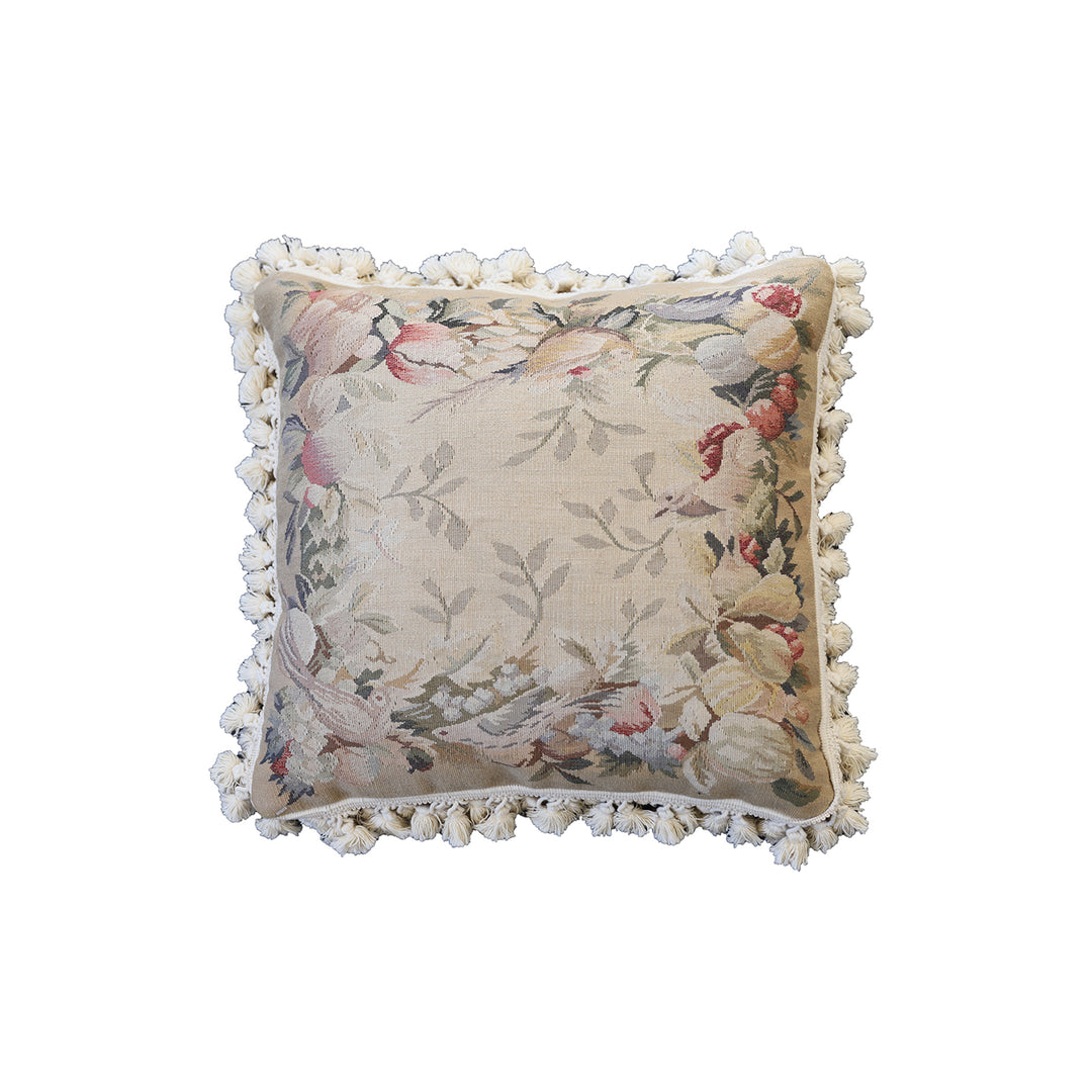 Handcrafted 18x18 cream and tan wool needlepoint cushion with botanical bird motifs and white tassel fringe by Ariana Rugs