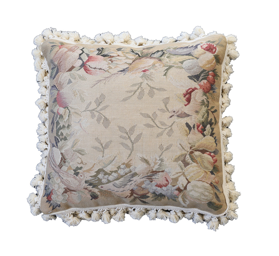 Handcrafted 18x18 cream and tan wool needlepoint cushion with botanical bird motifs and white tassel fringe by Ariana Rugs