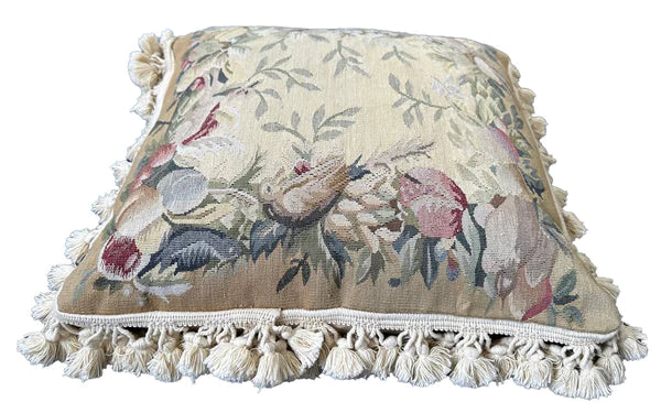 Handcrafted 18x18 cream and tan wool needlepoint cushion with botanical bird motifs and white tassel fringe by Ariana Rugs