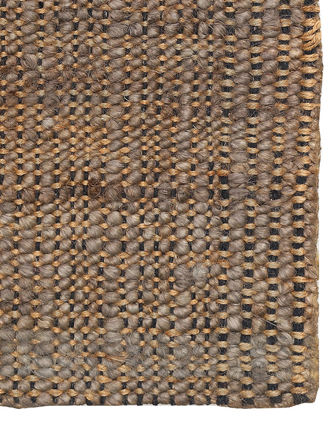 Close-up of a woven jute rug with a geometric pattern.