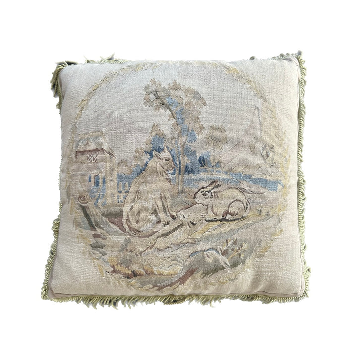 Handcrafted 24x24 beige and blue wool Aubusson style cushion featuring a whimsical animal motif and vibrant green fringe tassels by Ariana Rugs