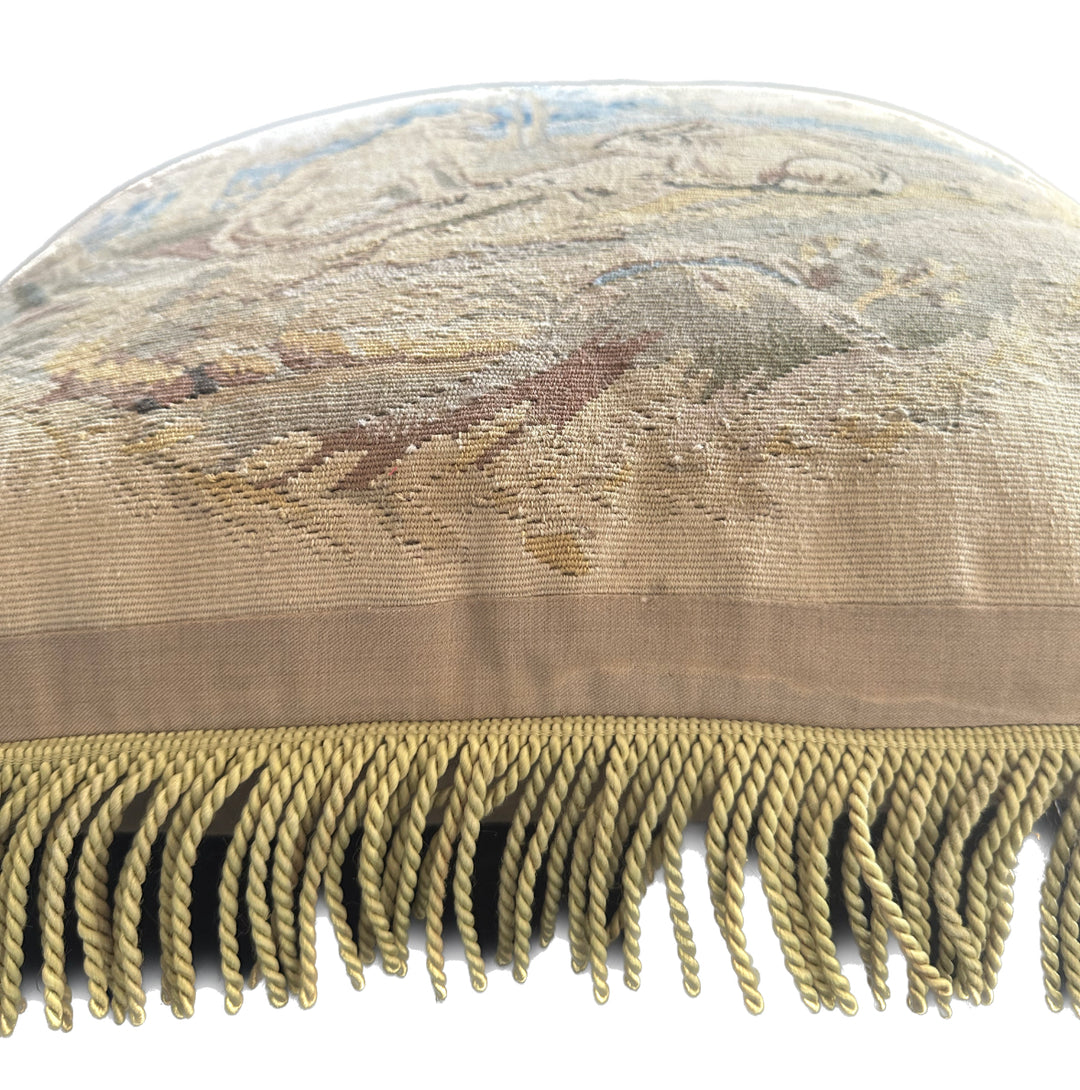 Handcrafted 24x24 beige and blue wool Aubusson style cushion featuring a whimsical animal motif and vibrant green fringe tassels by Ariana Rugs