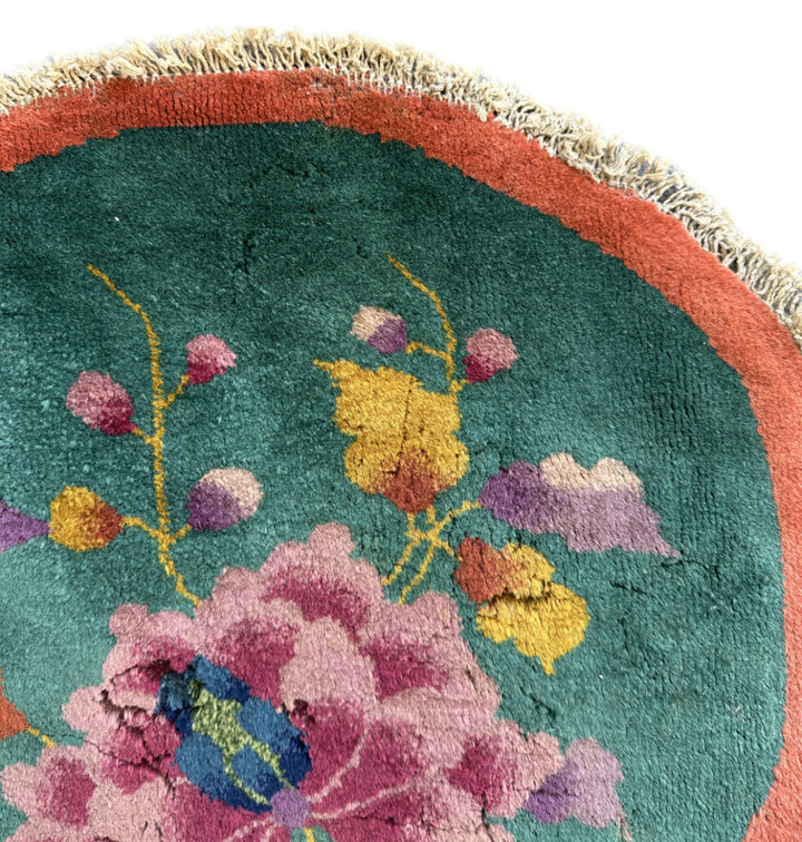 Close-up of a round rug with floral patterns and a colorful border.