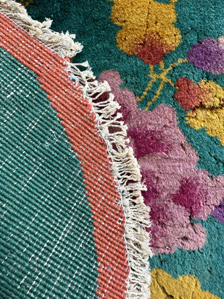 Close-up of a colorful floral-patterned rug with fringed edge.