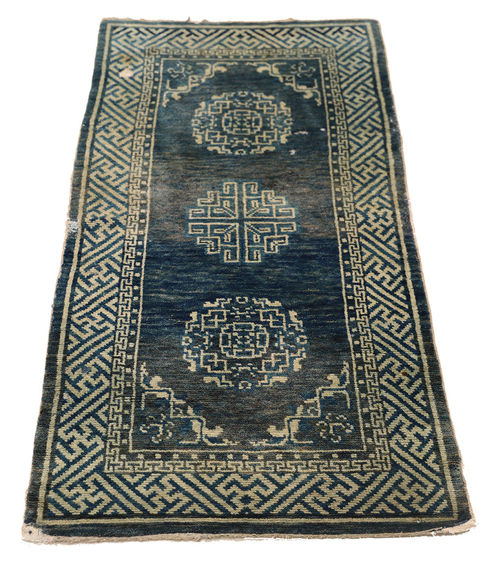 Vintage blue and beige rug with intricate patterns on a white background