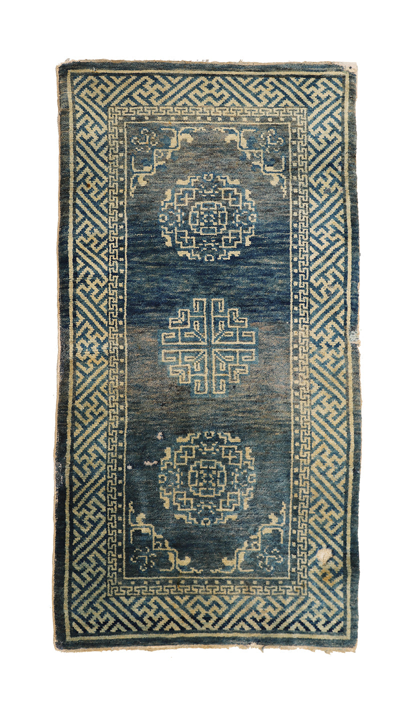 Vintage blue and beige rug with geometric patterns on a white background