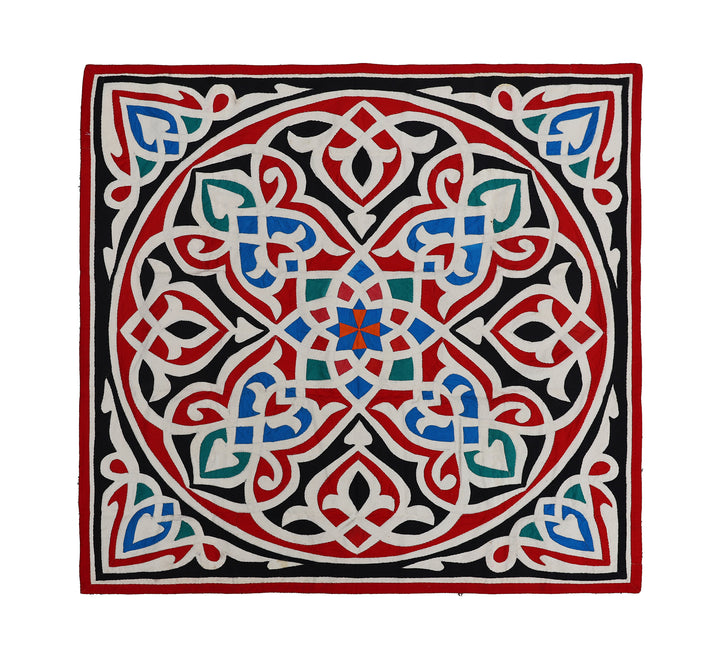 A square-shaped Egyptian appliqued tapestry with a geometric mosaic design featuring elements in red, green, blue, and white.