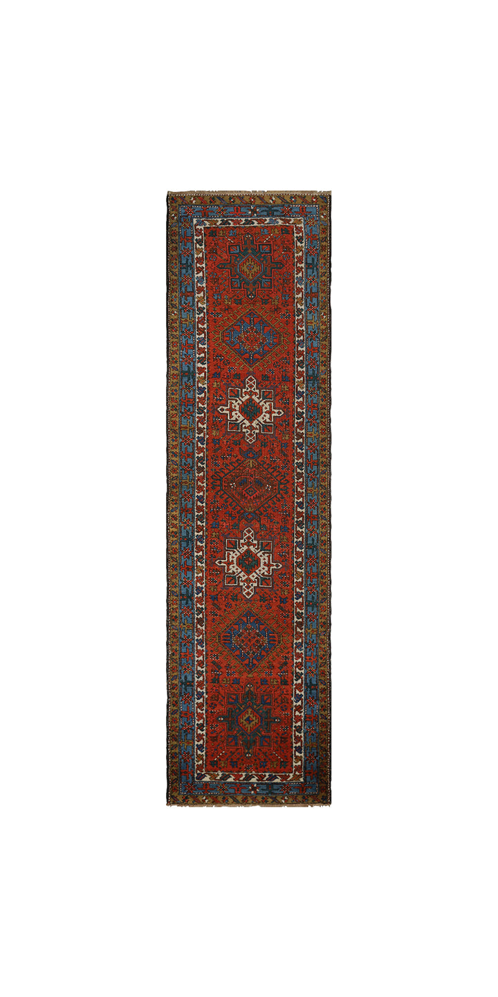 A long, narrow traditional runner rug with a deep red-brown field, blue and beige geometric motifs, and a patterned border, shown flat against a white background.