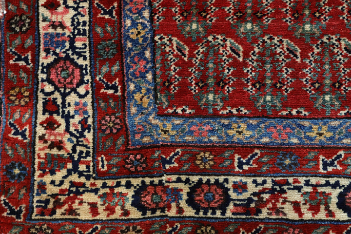 Antique Persian gallery runner (15'9" x 3'4") featuring a classic Paisley Boteh design on a red field with green, brown, and a wide white border.