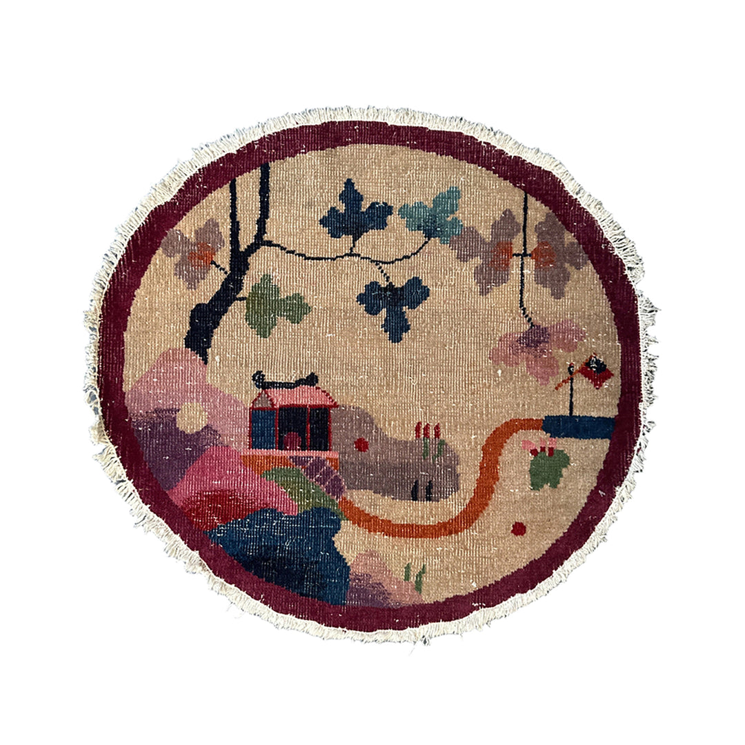 Round rug with a colorful design of a house, trees, and animals on a beige background.