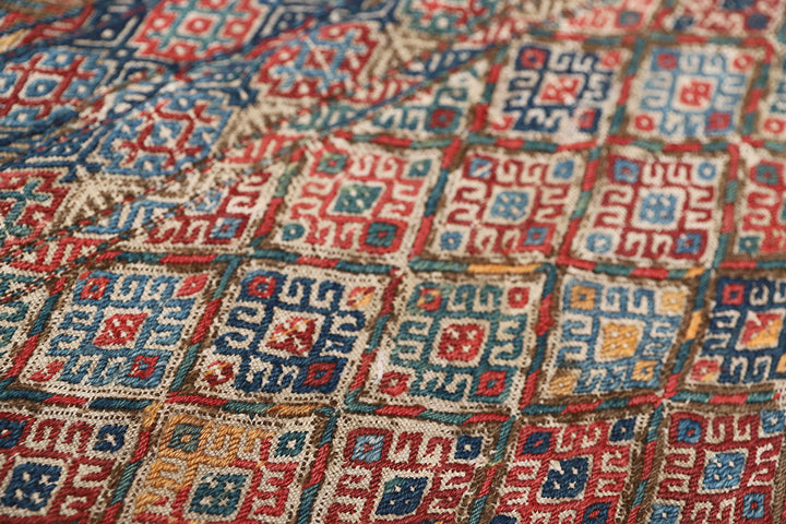 Close-up of a patterned fabric with red, blue, and beige colors.