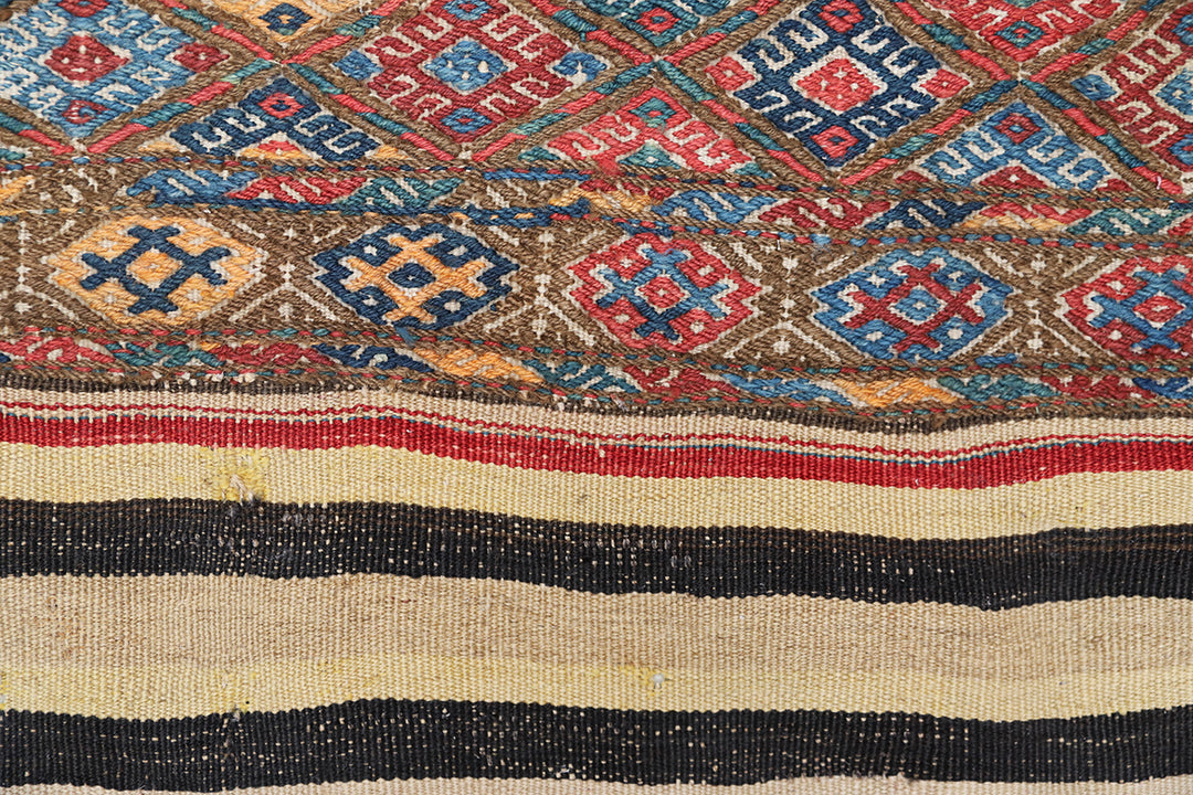 Close-up of a patterned fabric with geometric designs in red, blue, and beige.