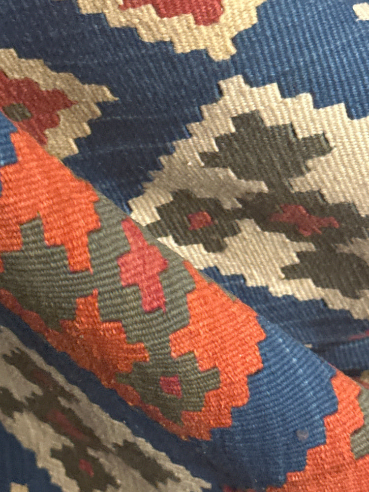 Close-up of a patterned fabric with blue, red, and beige colors.