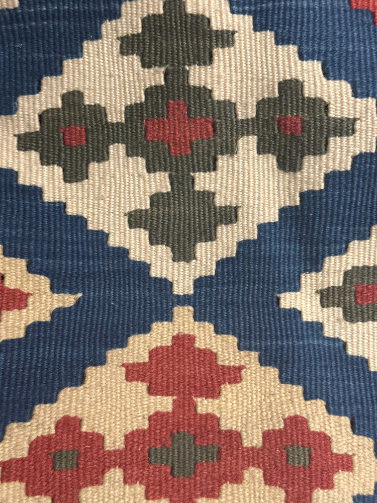 Close-up of a patterned fabric with geometric design in red, blue, and beige.