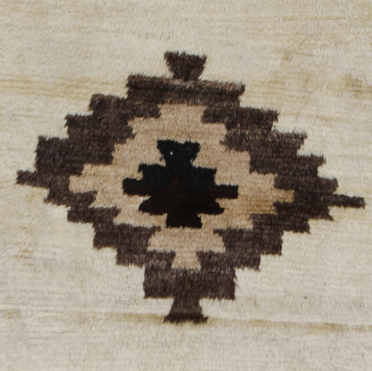 Close-up of a geometric patterned fabric with brown and black design on a beige background