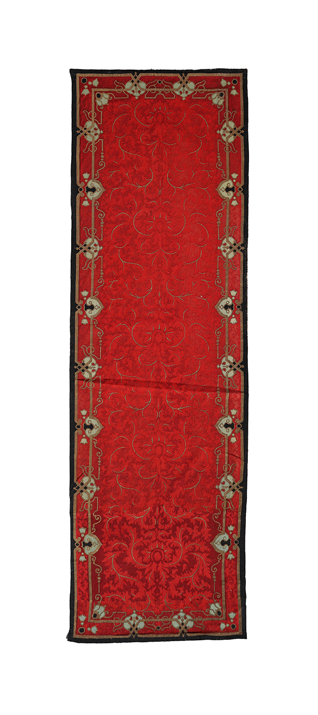 Red patterned rug with decorative border on a white background