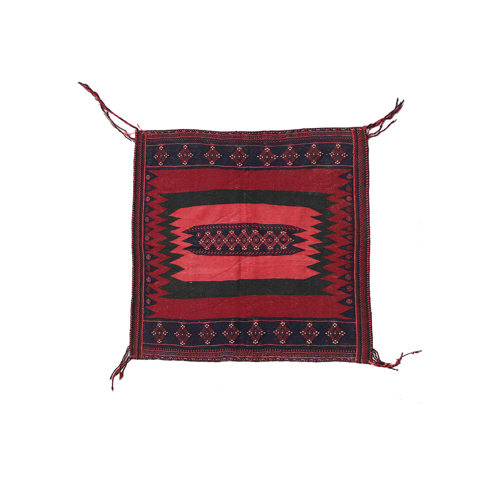 Decorative red and black patterned fabric with tassels on a white background