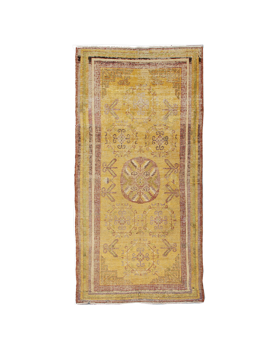 Yellow vintage rug with intricate patterns on a white background