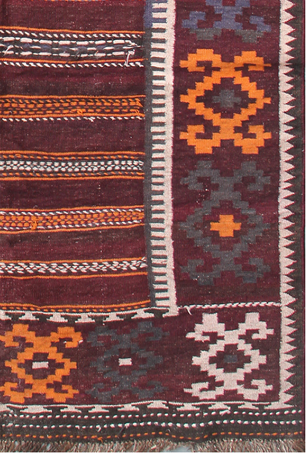 Close-up of a patterned rug with geometric designs in red, orange, and blue.