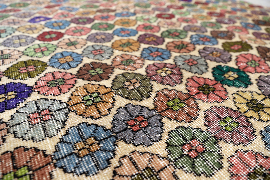 Close-up of a needlepoint fabric with floral patterns in various colors.