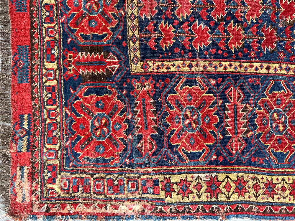 Close-up of a colorful patterned rug with red, blue, and beige colors.