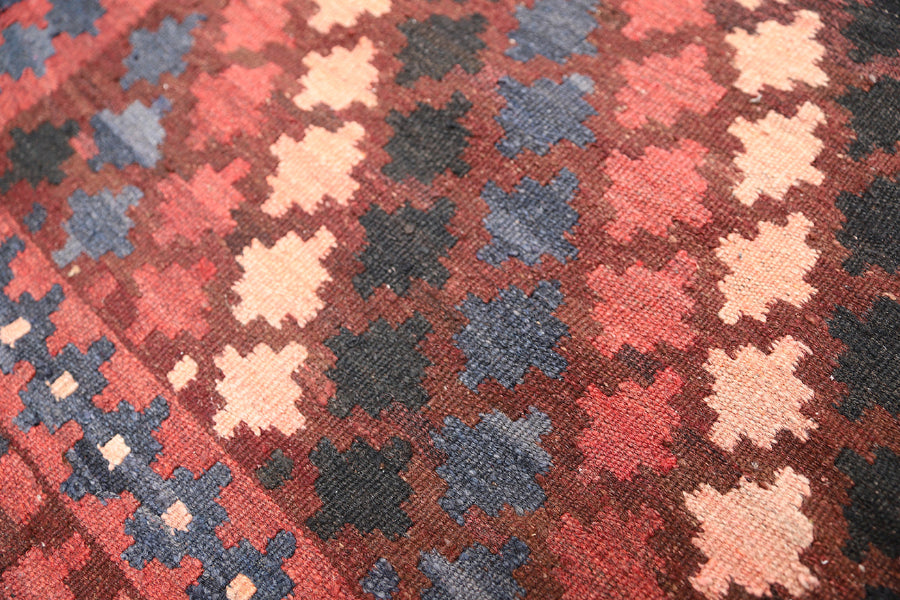 Close-up of a patterned fabric with red, blue, and beige colors.