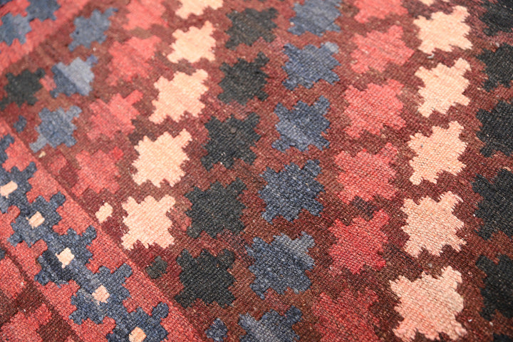 Close-up of a patterned fabric with red, blue, and beige colors.