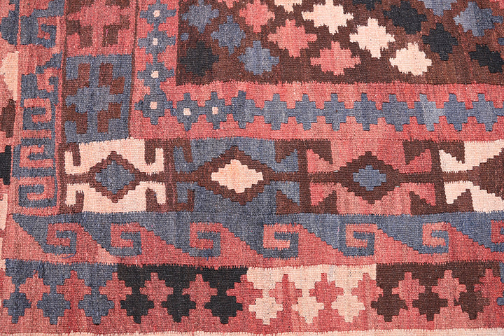 Close-up of a patterned rug with geometric designs in red, blue, and beige.