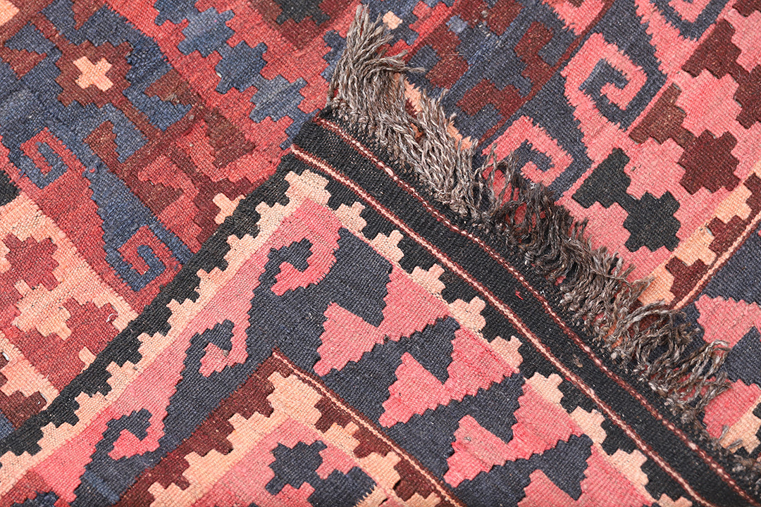 Close-up of a patterned rug with red, blue, and beige colors.