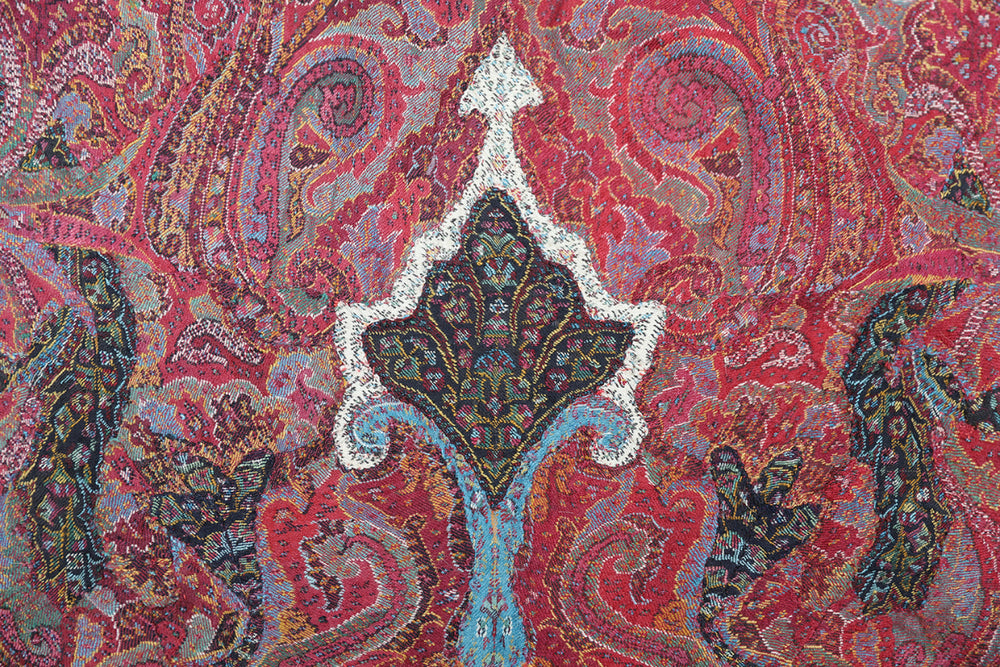 Close-up of a vibrant paisley pattern with intricate details on a red background.
