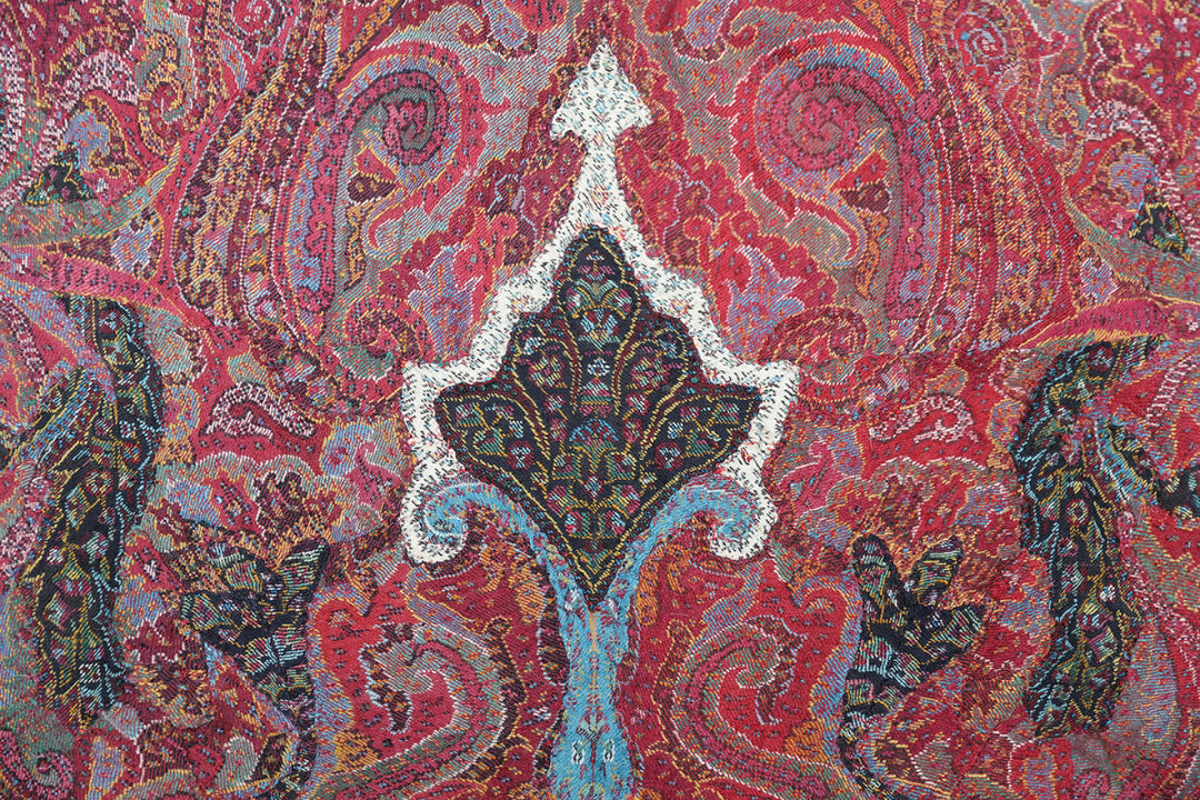Close-up of a vibrant paisley pattern with intricate details on a red background.