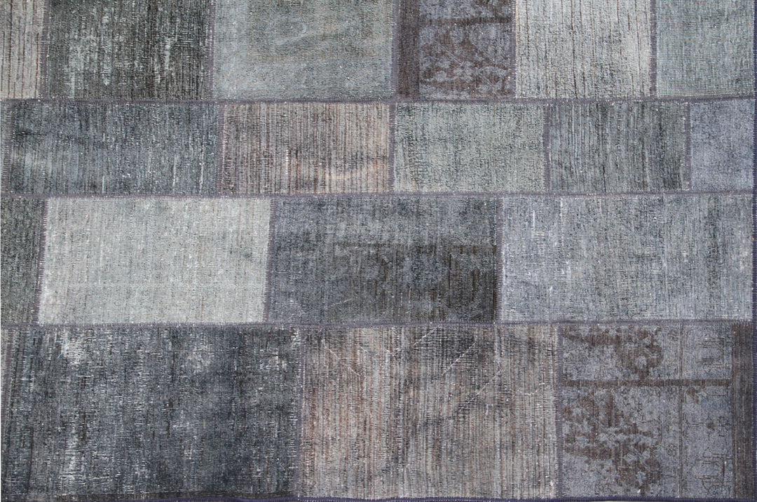 Patchwork rug with rectangular tiles in various shades of gray and brown.