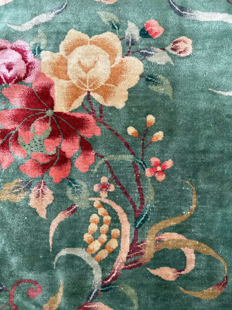 Floral patterned rug with red, pink, and yellow flowers on a green background