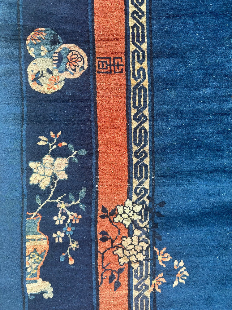 Close-up of a traditional rug with floral patterns and Chinese characters.