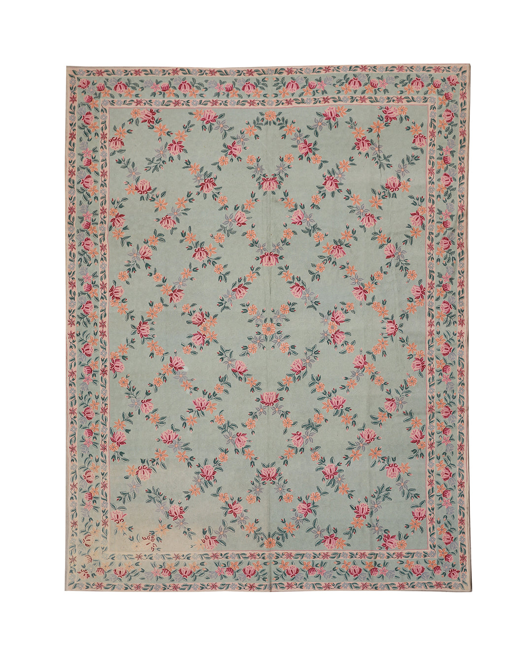 Floral patterned rug with pink and green flowers on a light blue background