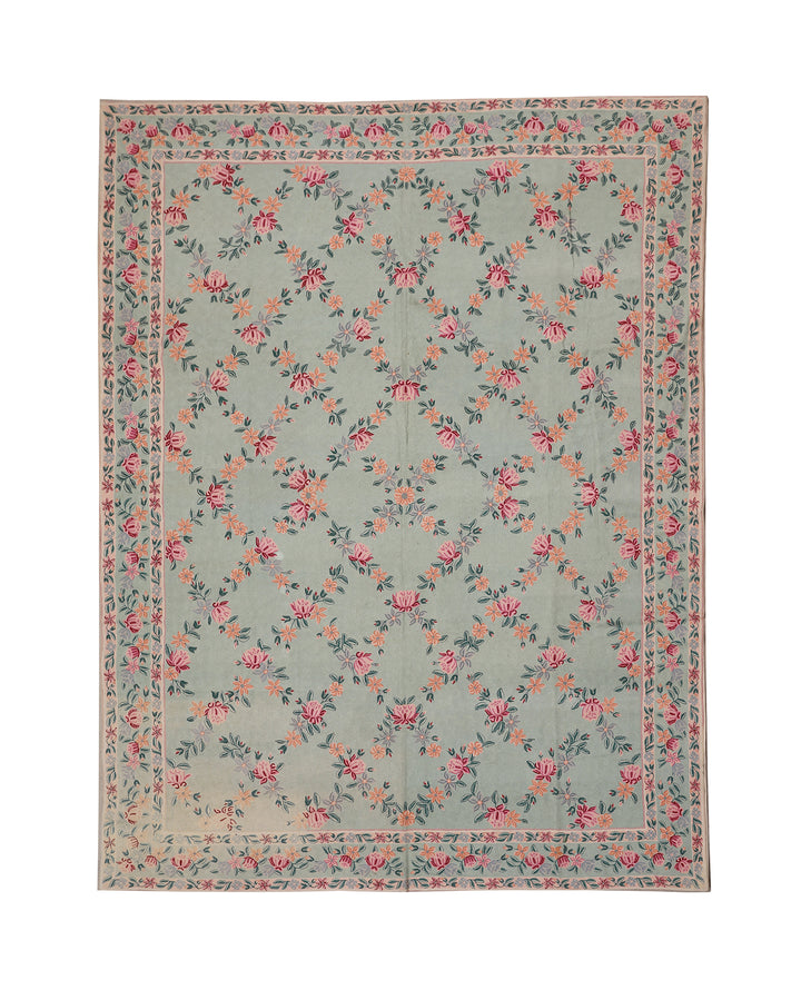 Floral patterned rug with pink and green flowers on a light blue background