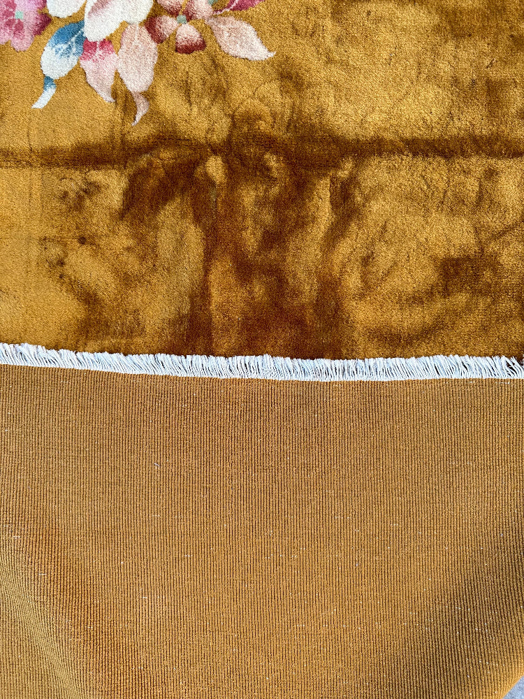 Close-up of a brown fabric with floral embroidery at the top corner