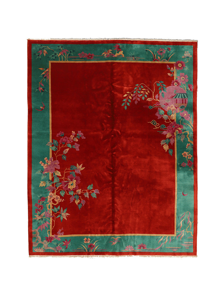 Decorative rug with red center and green border featuring floral patterns on a white background