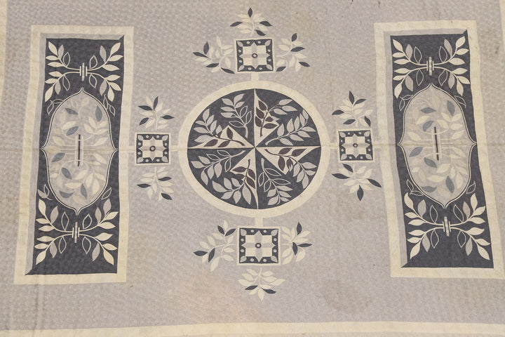 A vintage European chainstitched area rug with geometric patterns in gray, black, and white colors on a beige background.