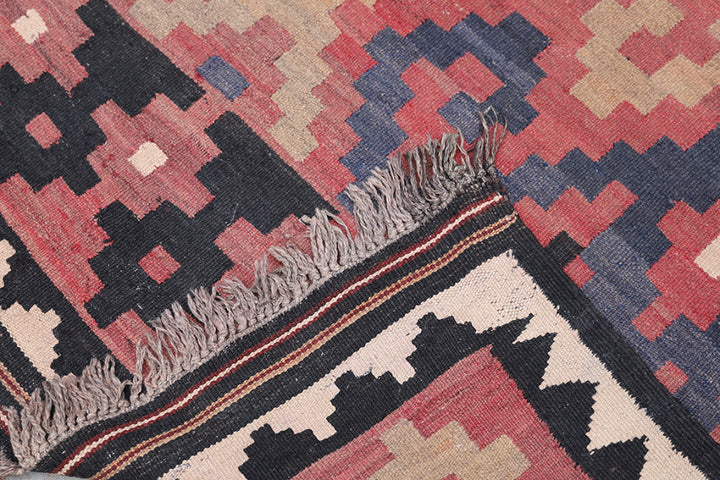 Close-up of a patterned rug with geometric designs in red, black, and beige.