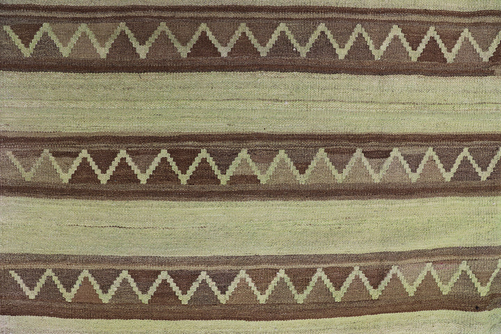 Handwoven green overdyed wool kilim with brown accents and geometric tribal design, crafted by Uzbek artisans in Afghanistan. Luxury flatweave from the Ariana Kilim Collection.