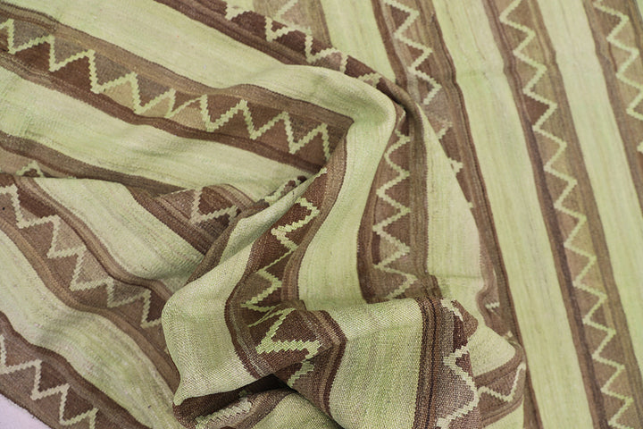 Handwoven green overdyed wool kilim with brown accents and geometric tribal design, crafted by Uzbek artisans in Afghanistan. Luxury flatweave from the Ariana Kilim Collection.