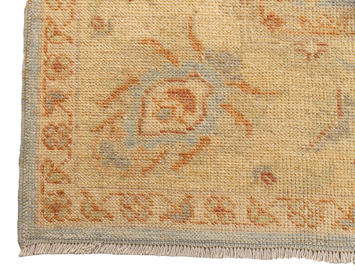 Hand-knotted 8'1" x 9'7" Afghan Oushak rug featuring a soft sky blue field with a sand goldish yellow border and terracotta and cream floral motifs.